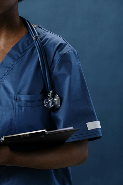 Foto de um enfermeiro usando uniforme azul e segurando uma prancheta e com um estetoscópio pendurado no pescoço